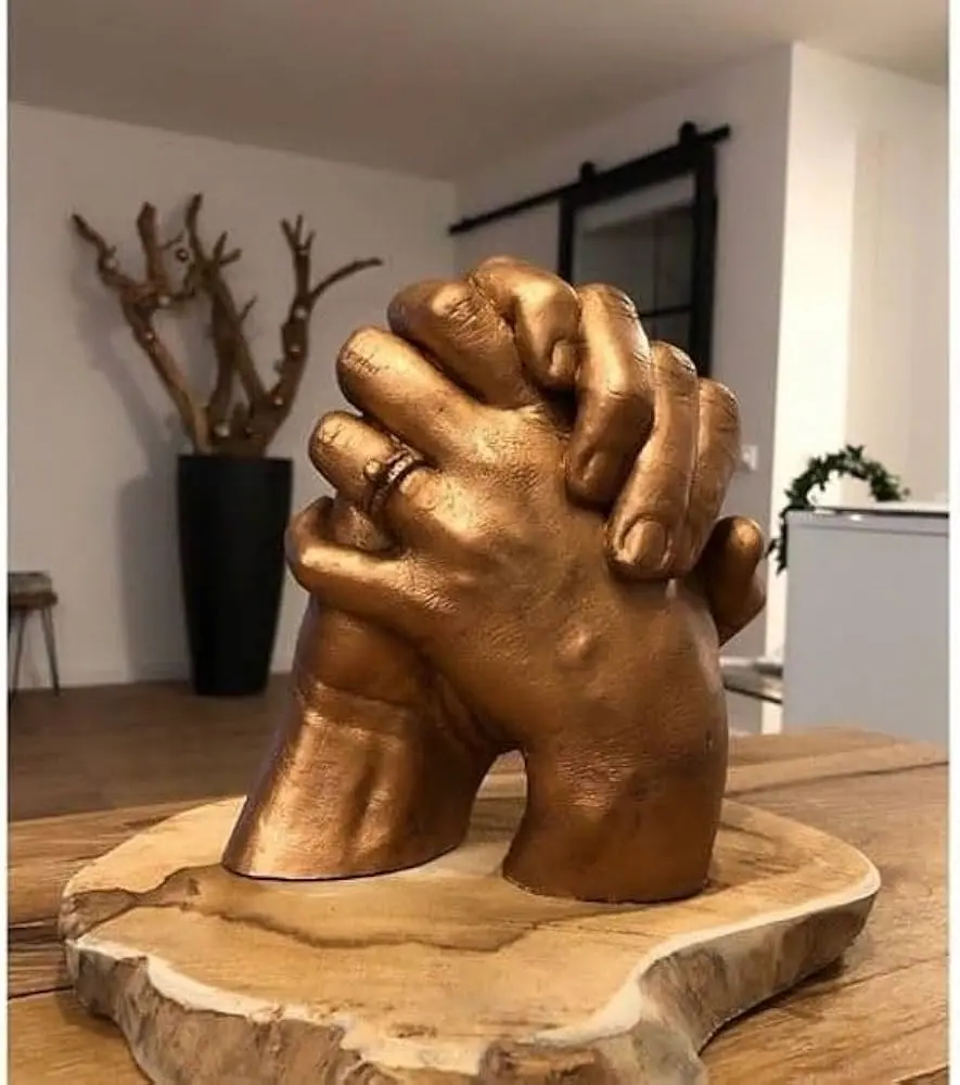 Interlocked hands of couple cast in bronze-effect resin on elegant wooden display stand, showing romantic connection and anniversary celebration